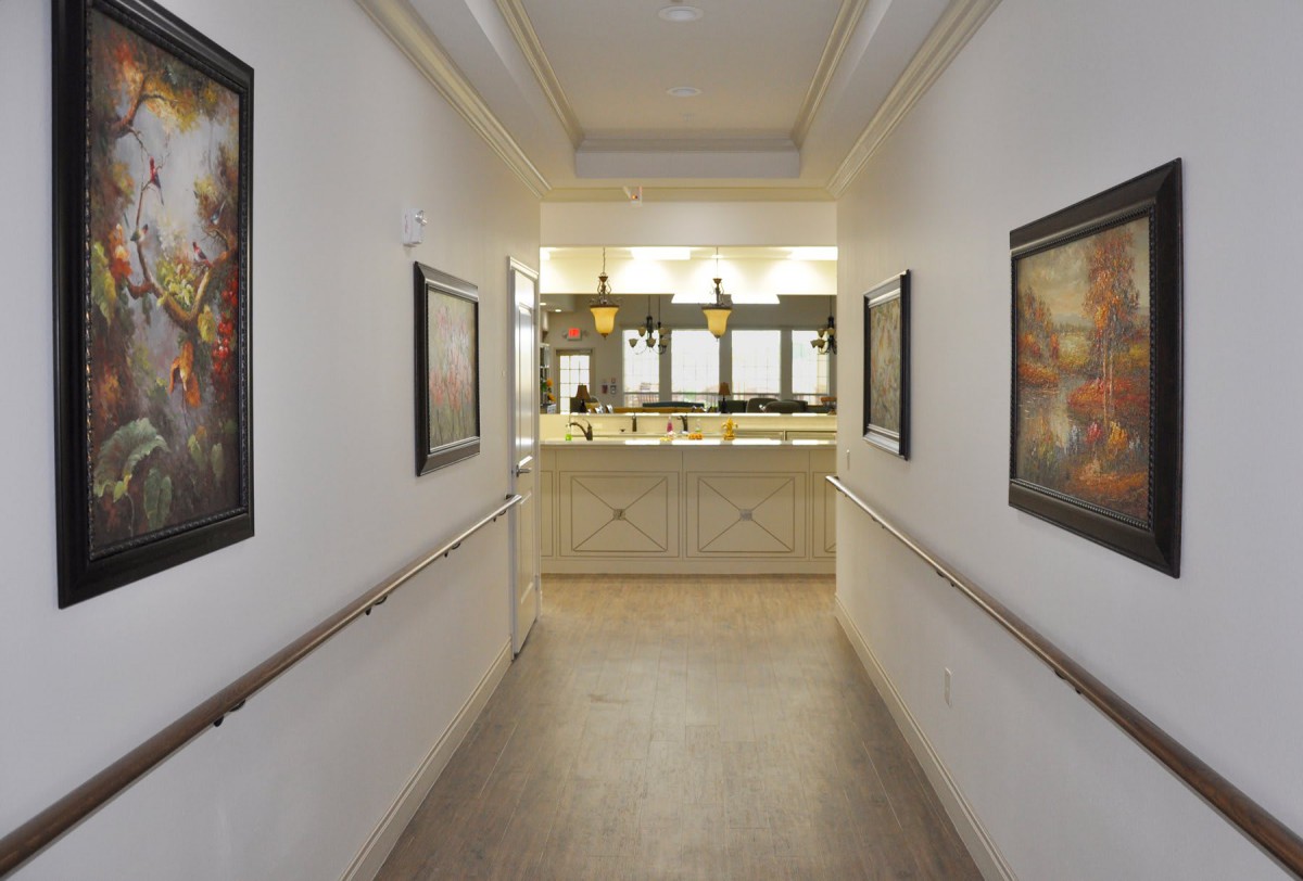 A well-lit hallway with artwork adorning the walls leads to a reception area.