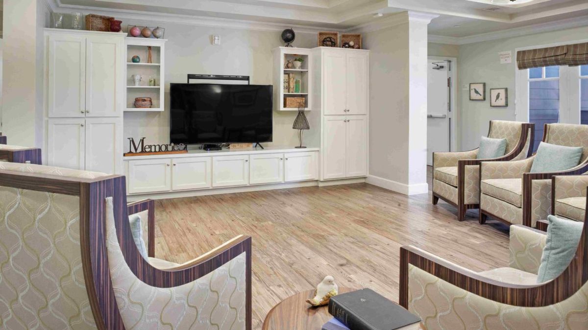 A cozy living room with a television, bookshelves, and wood flooring.