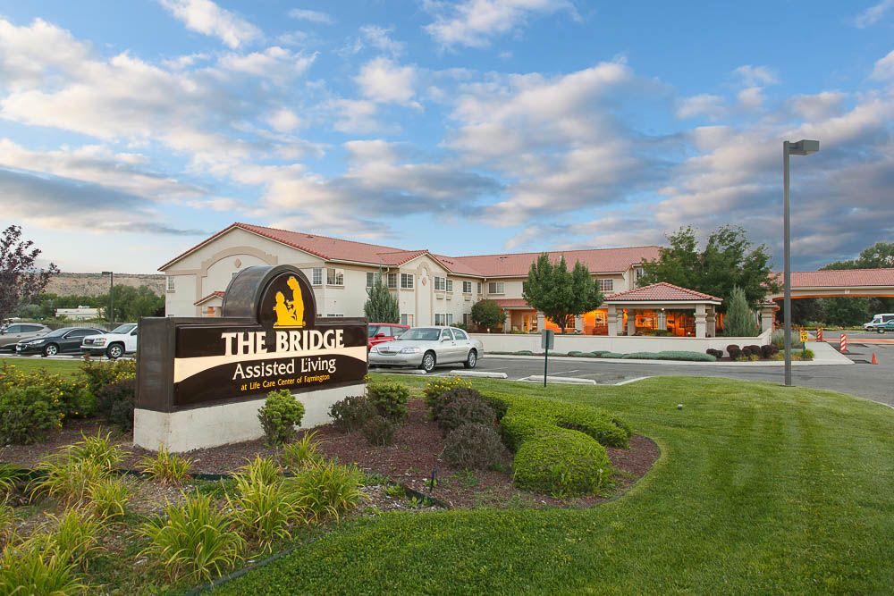 A hotel building with a sign reading 'The Ridge' surrounded by well-maintained gardens and a cloudy sky backdrop.