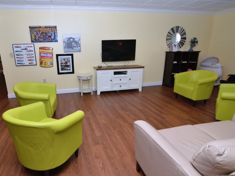 A cozy living room with a television, colorful armchairs, and decorative wall art.