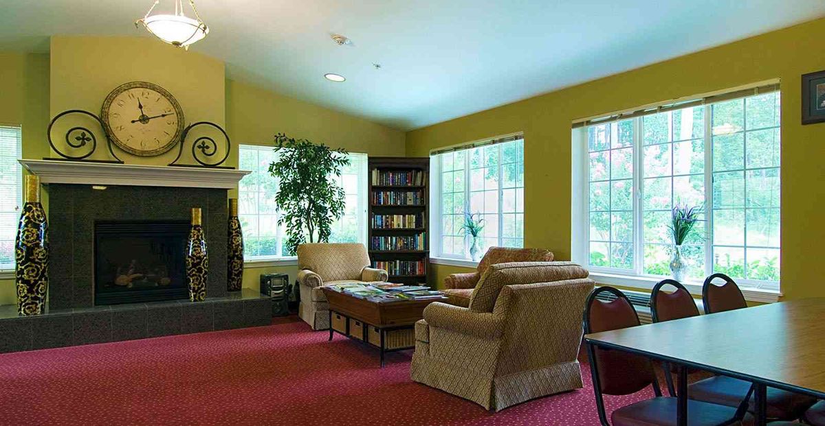 A cozy living room with armchairs, a fireplace, and a bookshelf.