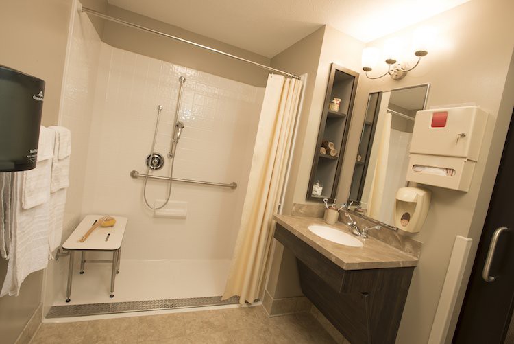An accessible bathroom with a walk-in shower, grab bars, and a vanity sink.