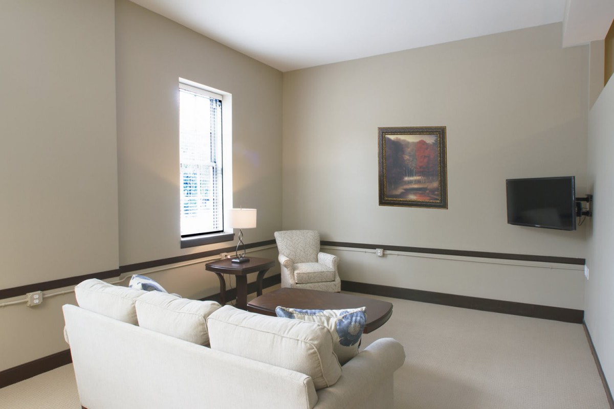 A cozy living room with a sofa, armchair, coffee table, and artwork.