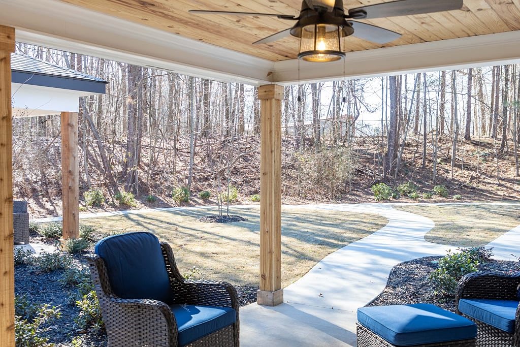A cozy covered patio with wicker chairs, offering a scenic view of the forest.