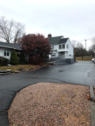 A cozy residential house with a winding driveway and surrounding trees, captured on a cloudy day.
