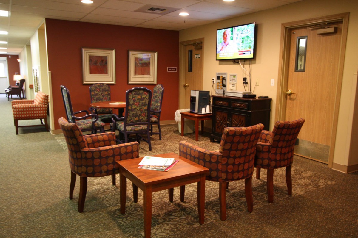 A cozy waiting room with chairs arranged around a table and a television on the wall.