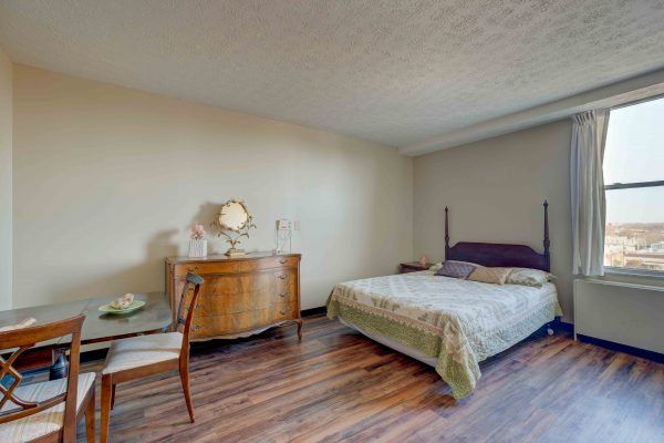 A minimalist bedroom with wooden flooring and classic furniture.