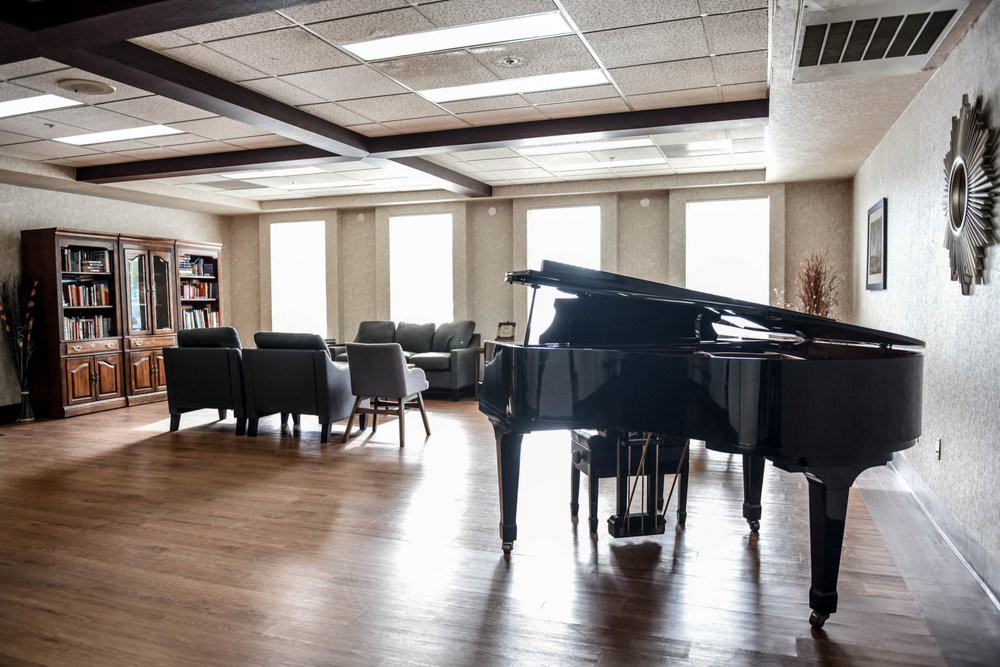 A spacious living room featuring a grand piano and modern furniture.