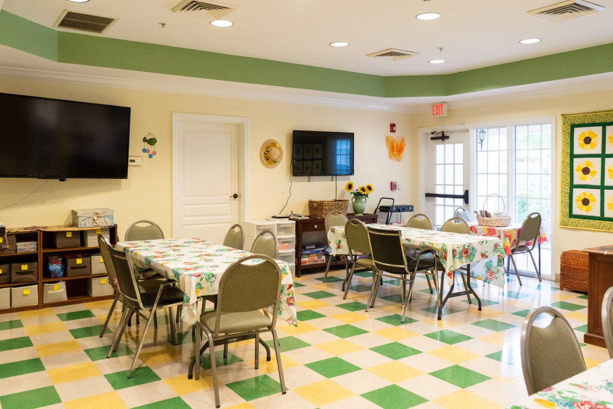 A community room with tables, chairs, and TVs, suitable for meetings or gatherings.