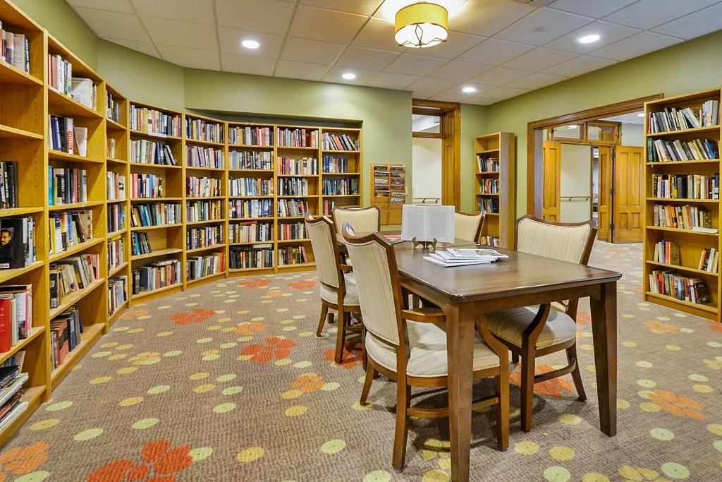 A cozy library interior with bookshelves and a reading table.