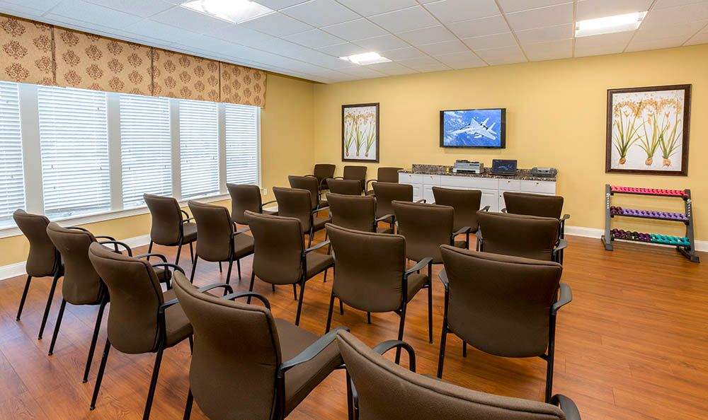 An empty conference room set up for presentations with rows of chairs facing a television.