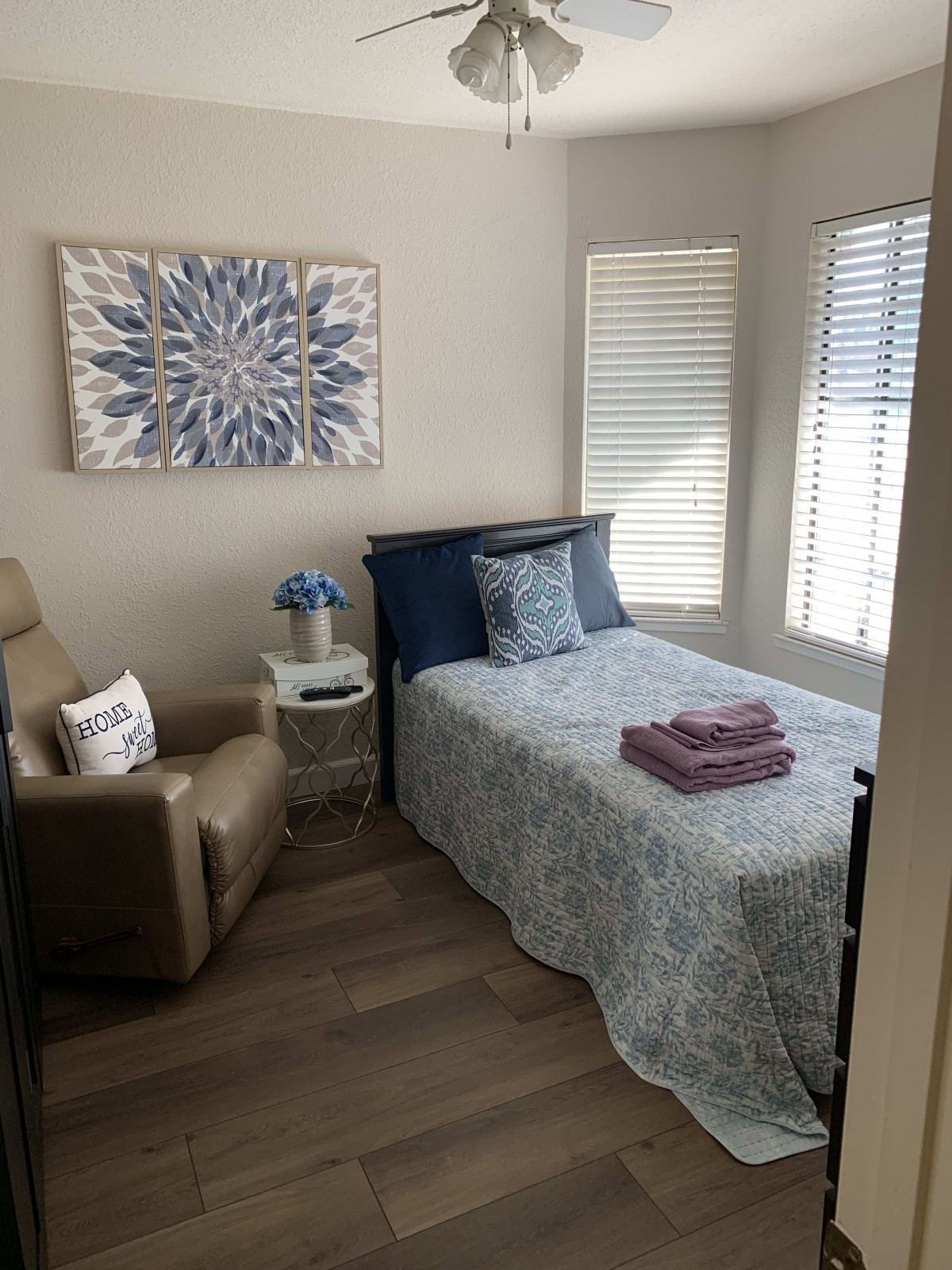 A cozy and well-decorated bedroom featuring a bed, recliner chair, and wall art.