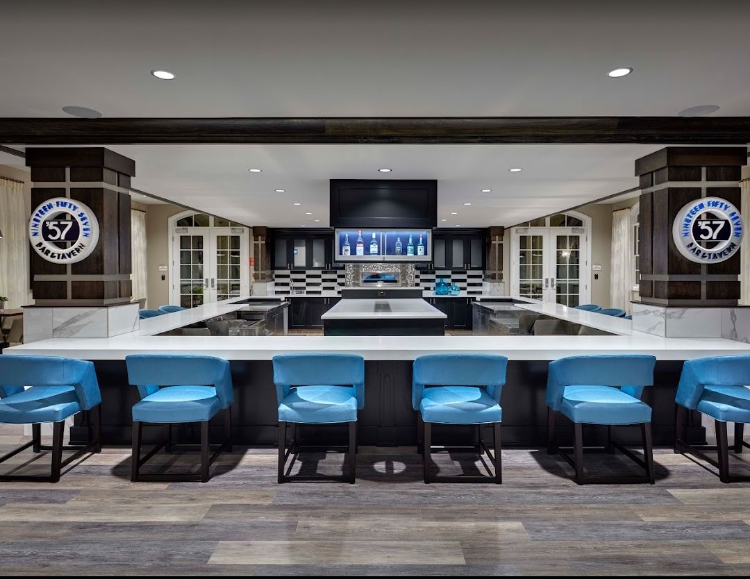 A modern bar with blue chairs, a large counter, and sleek interior design.