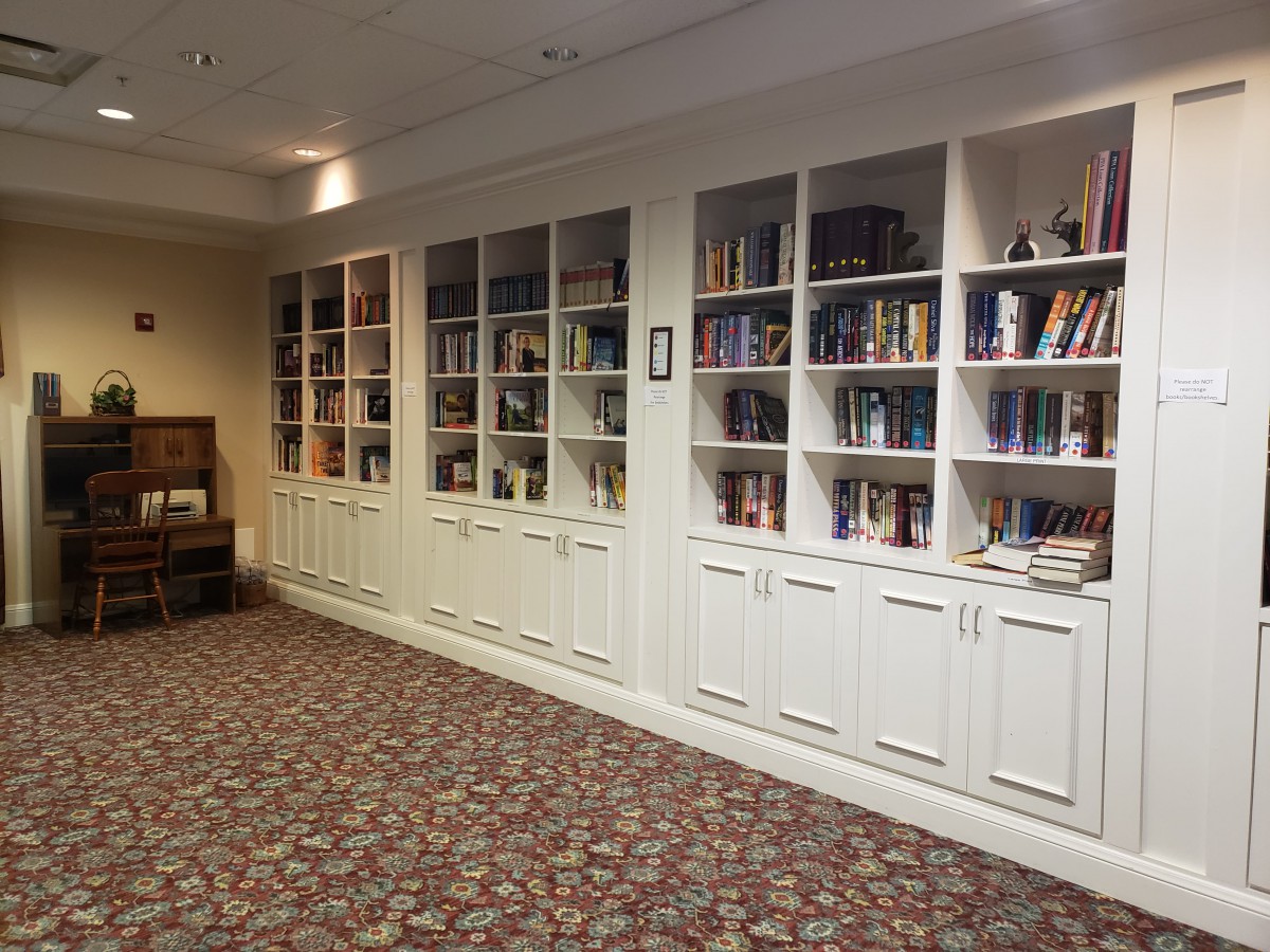 A cozy library area with built-in bookshelves filled with various books, and a carpeted floor.