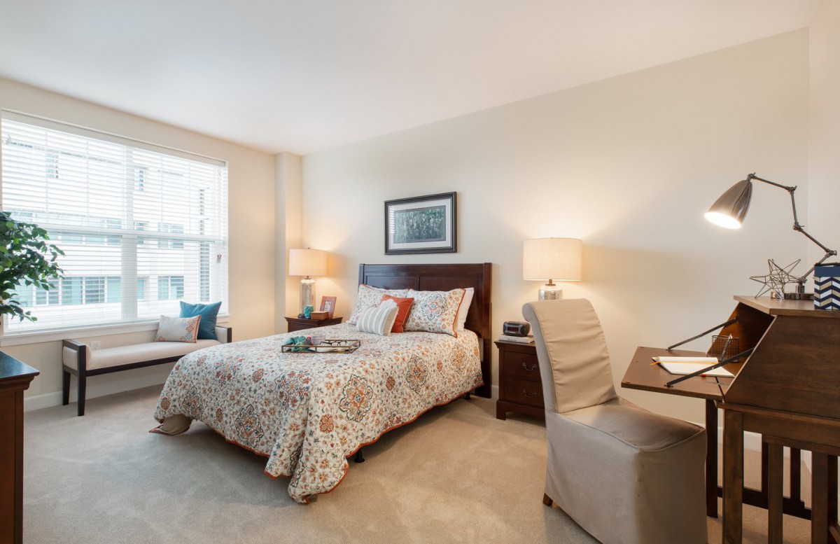 A cozy and well-decorated bedroom with a large bed, lamps, and a comfortable chair by the window.