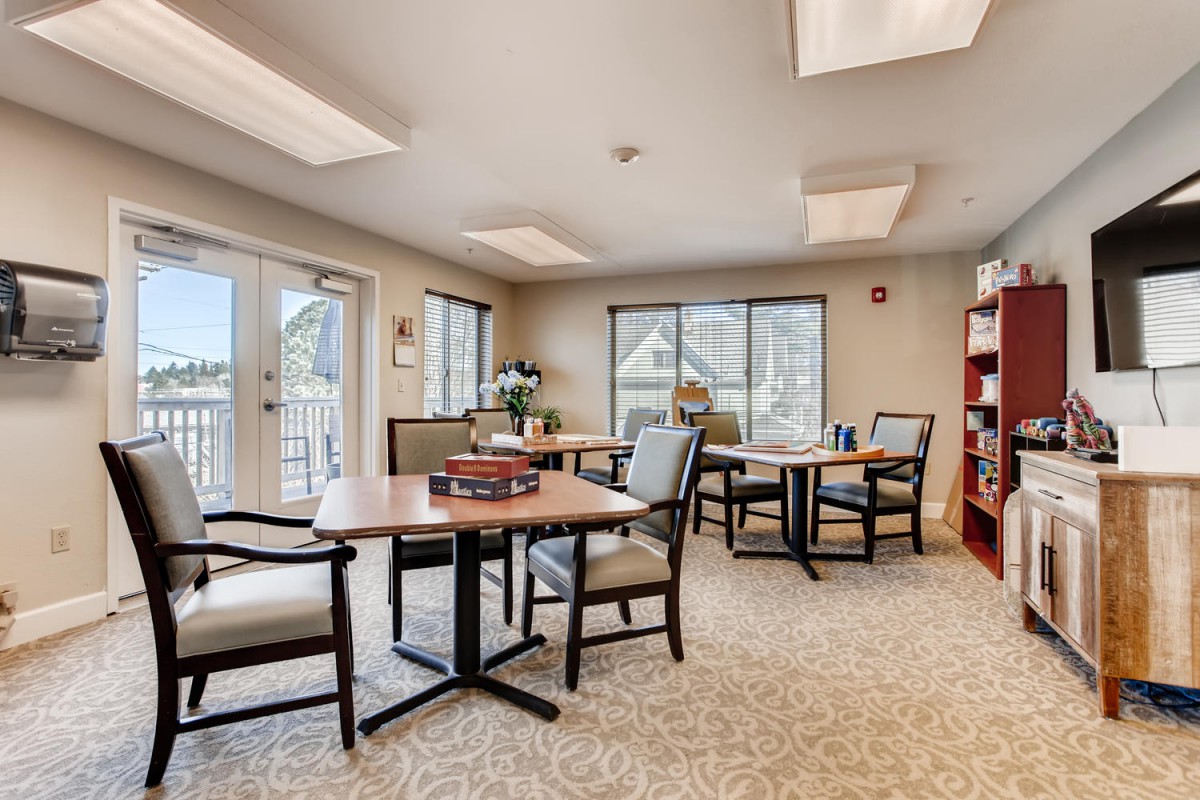 A bright and spacious office meeting room with tables, chairs, and natural lighting from large windows.