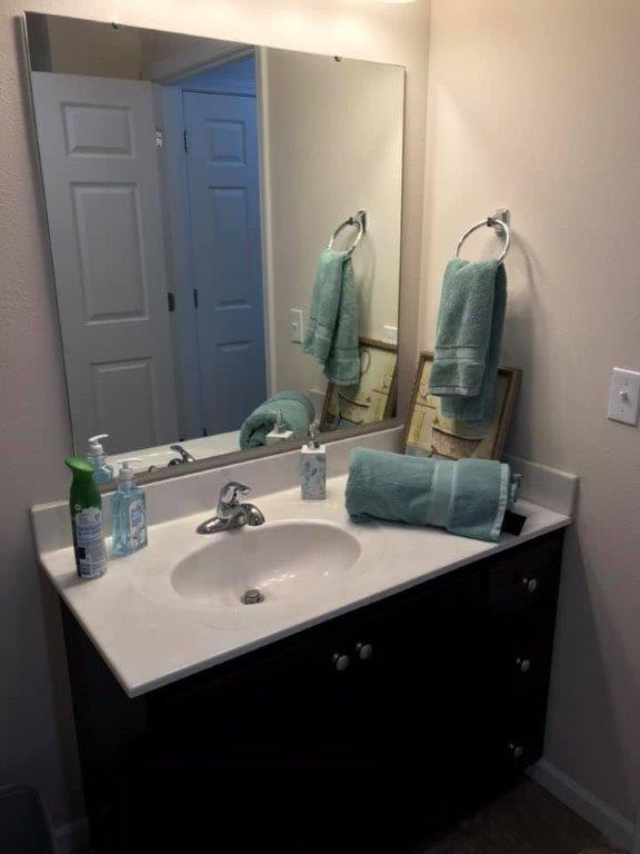 A tidy bathroom sink area with teal towels and a mirror.