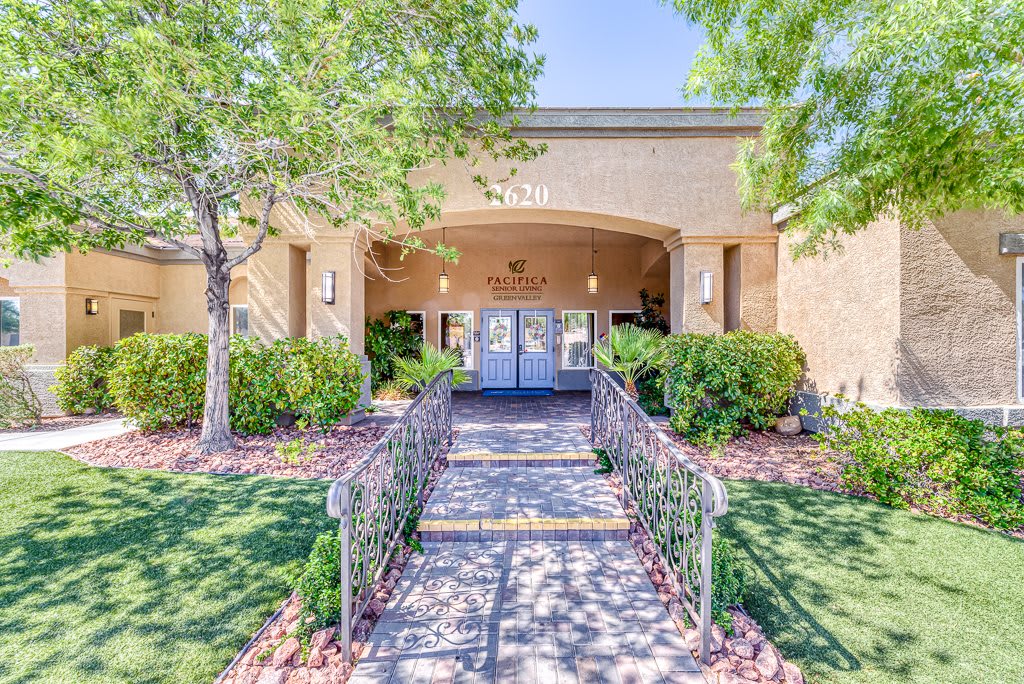 An inviting building entrance surrounded by greenery and a pathway.