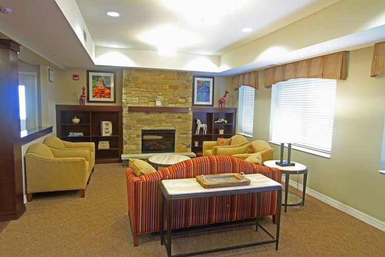 A cozy living room with comfortable seating, a stone fireplace, and decorative artwork.