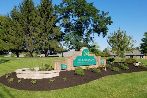A welcoming sign for 'The Delphian' surrounded by lush greenery and clear blue skies.