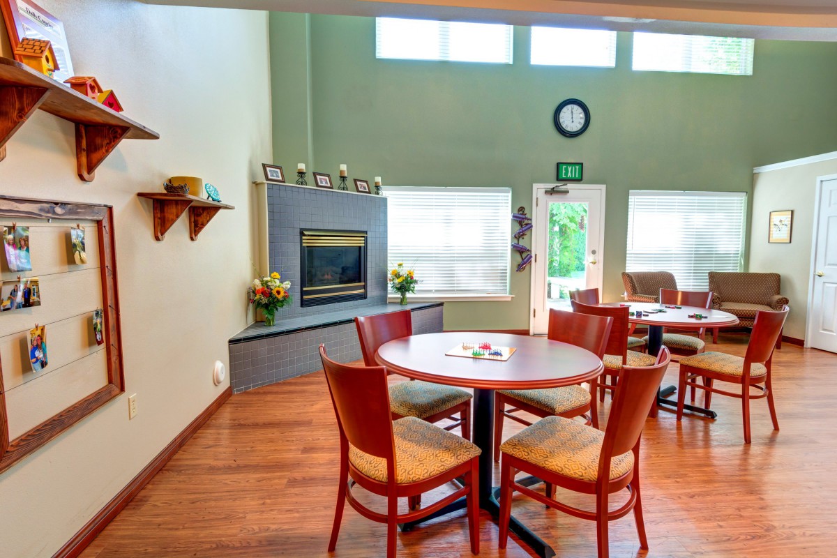 A cozy dining area with a round table, chairs, and a fireplace in a modern interior setting.