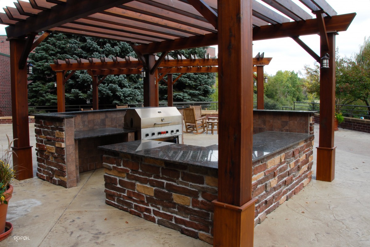 A well-designed outdoor kitchen with a grill and pergola, perfect for backyard barbecues.