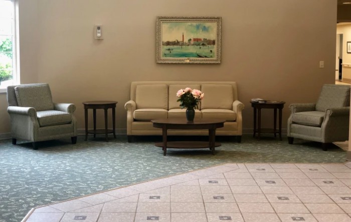 A cozy lobby area featuring a sofa, coffee table with flowers, and artwork on the wall.