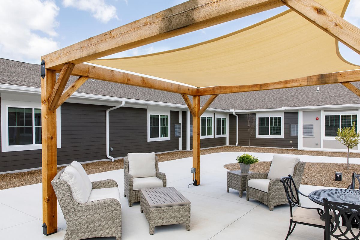 A comfortable outdoor patio with wicker seating and a wooden shade structure.