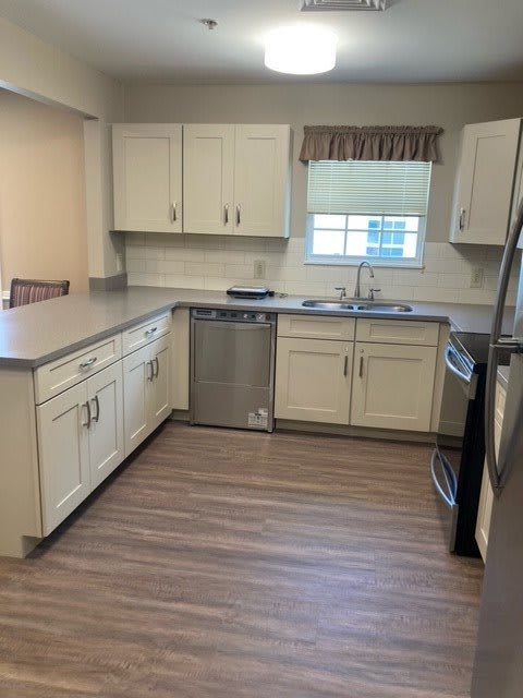 A modern kitchen with white cabinets, stainless steel appliances, and a hardwood floor.