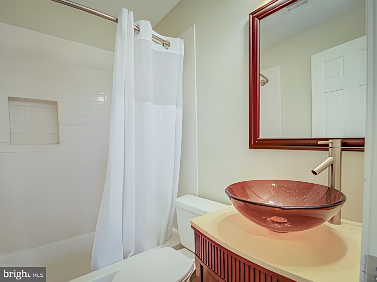 A modern bathroom featuring a glass sink and a shower with a white curtain.