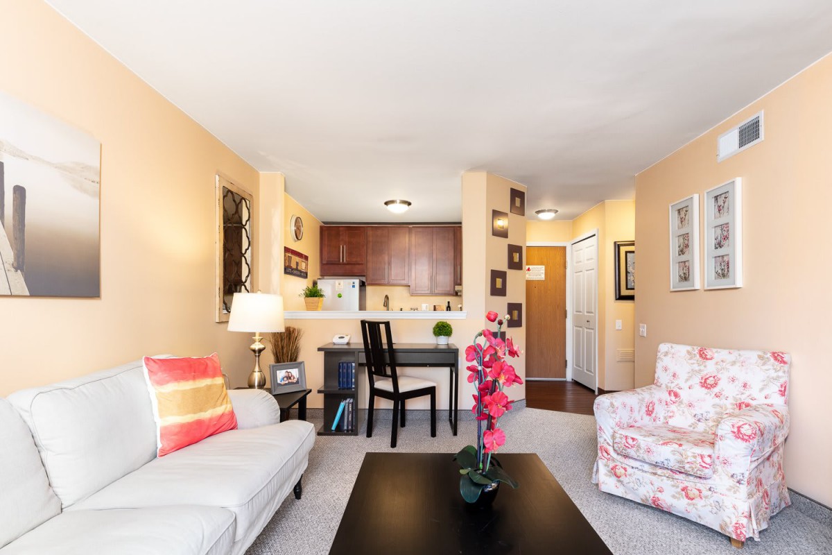 A cozy living room with a view into the kitchen, featuring comfortable seating and stylish decor.