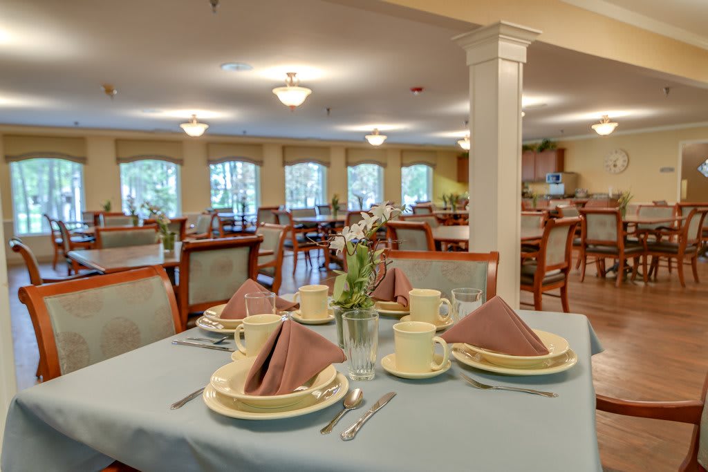 An elegantly set dining room table with plates, cups, and folded napkins in a well-lit restaurant.