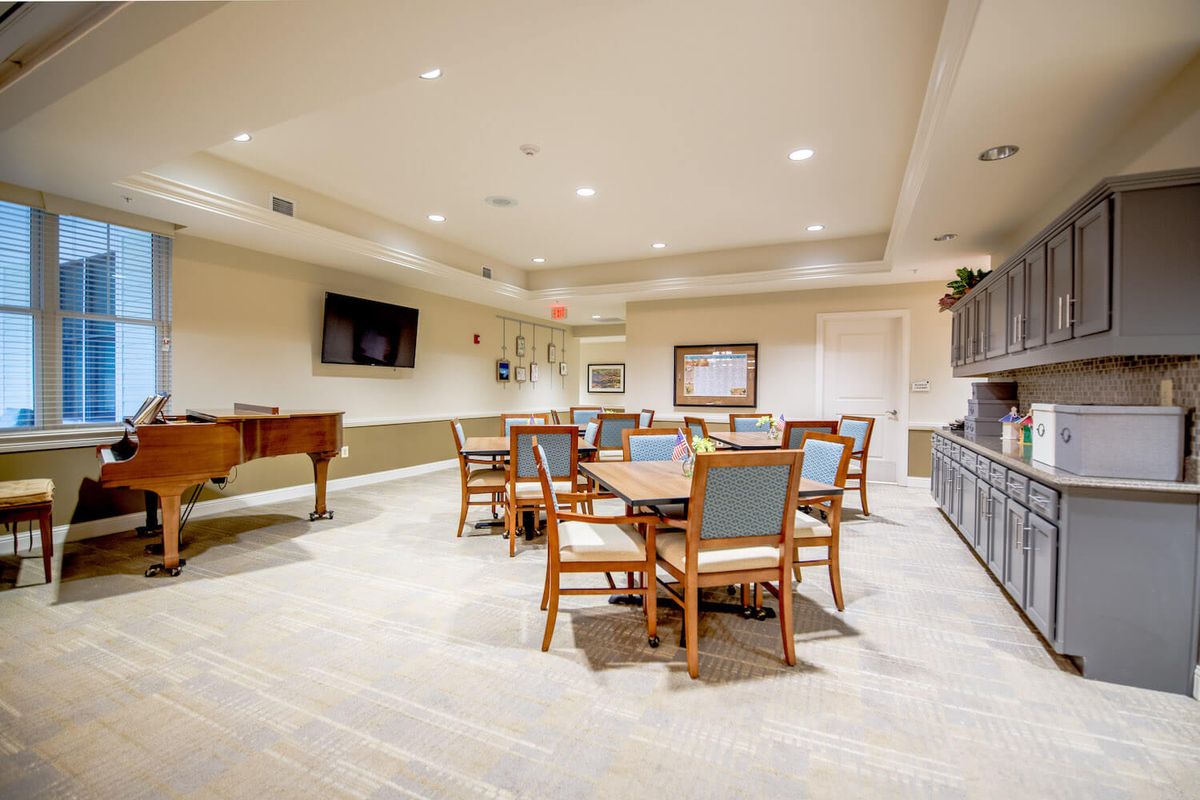 A well-furnished recreation room with tables, chairs, and a pool table.