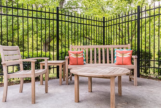 Wooden patio furniture set with colorful cushions in a garden setting.