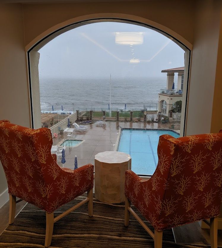 A cozy indoor seating area with a view of the pool and ocean beyond.