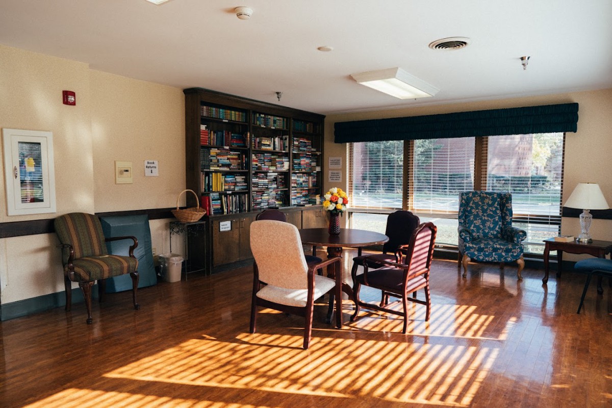A cozy living area with comfortable seating, bookshelves, and ample sunlight streaming through large windows.