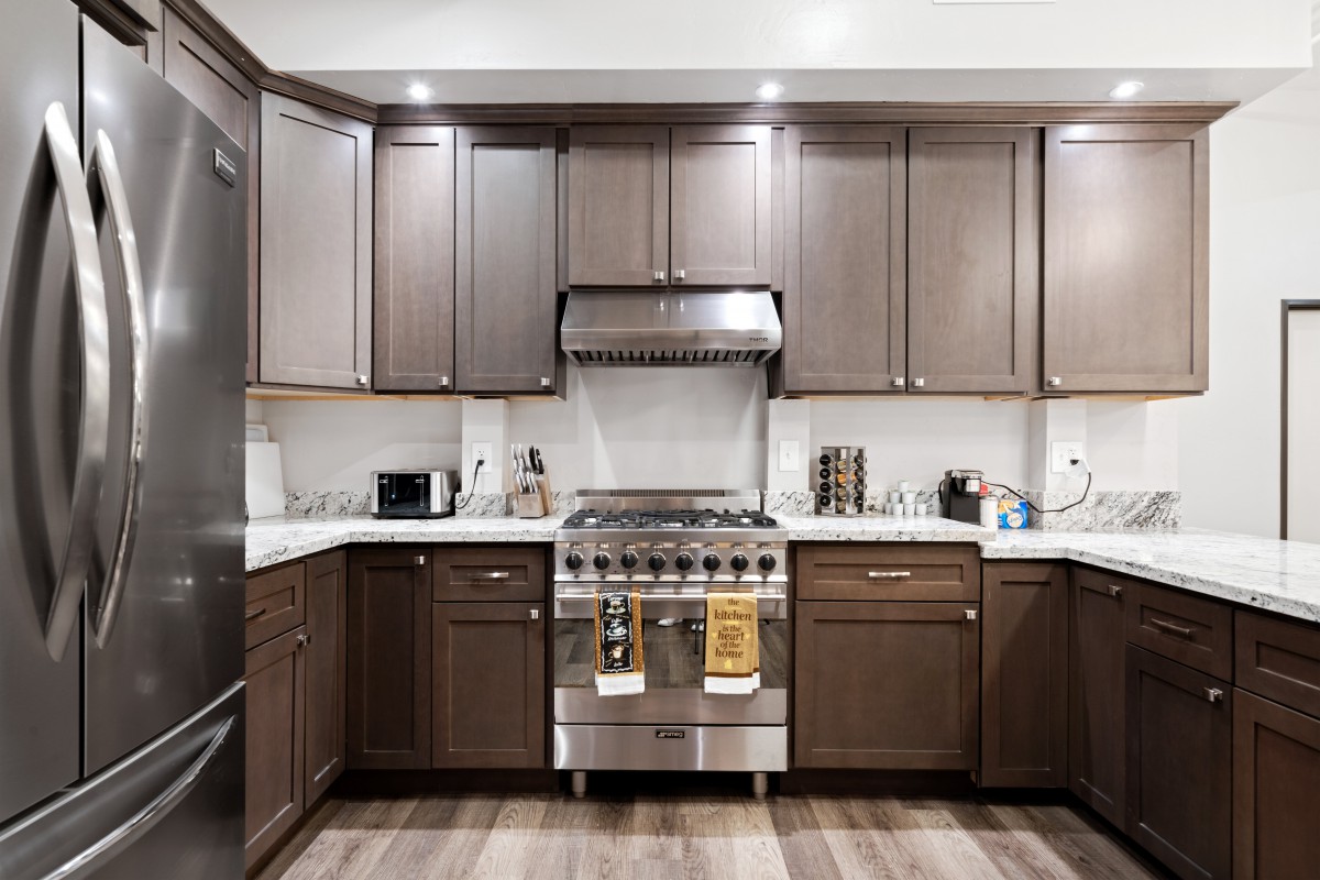 A modern kitchen with dark cabinets and stainless steel appliances.