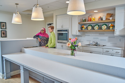 A bright and modern kitchen featuring two people engaged in conversation while surrounded by floral arrangements and stylish decor.
