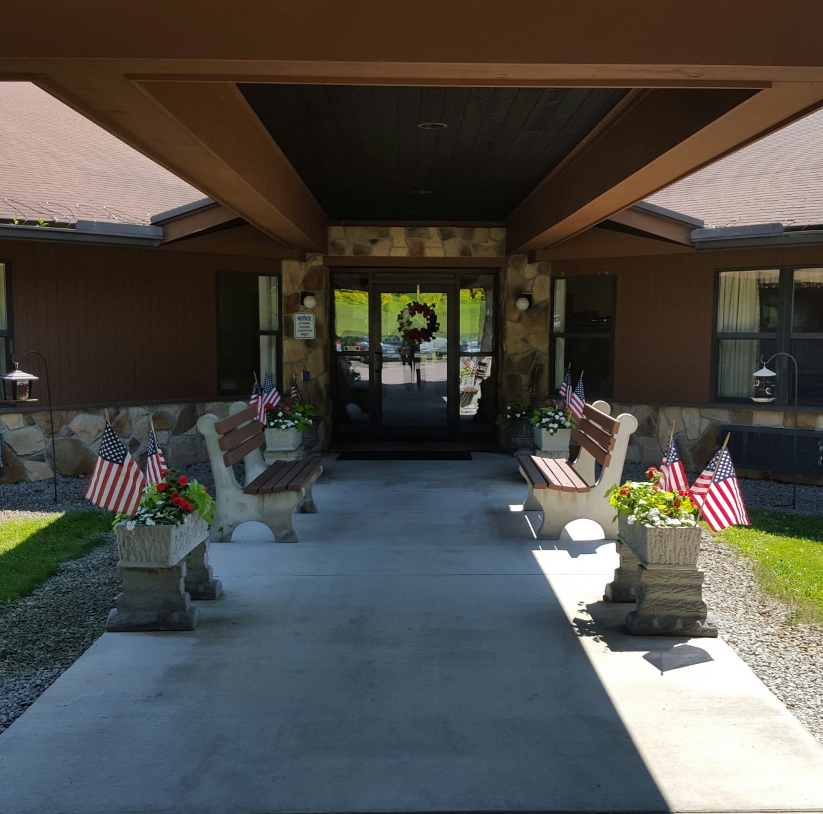 Entrance of a building decorated with American flags and benches on either side.