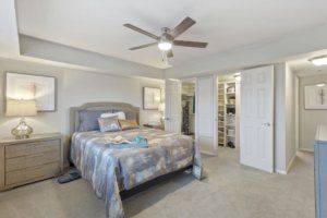A well-decorated bedroom featuring a cozy bed, ceiling fan, and spacious closet.