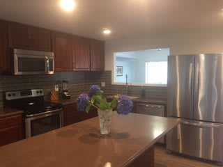 A modern kitchen with stainless steel appliances and a vase of flowers on the island.