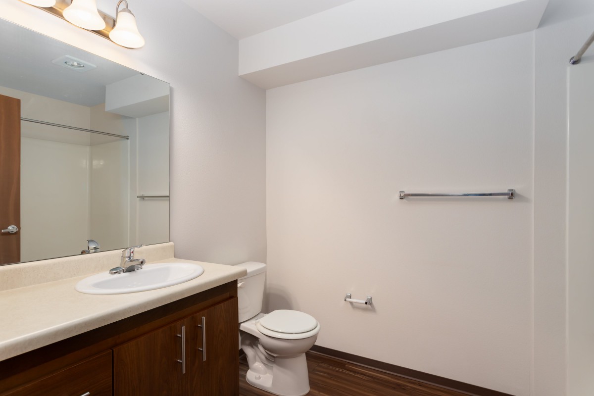 A minimalist bathroom with a sink, toilet, and mirror.
