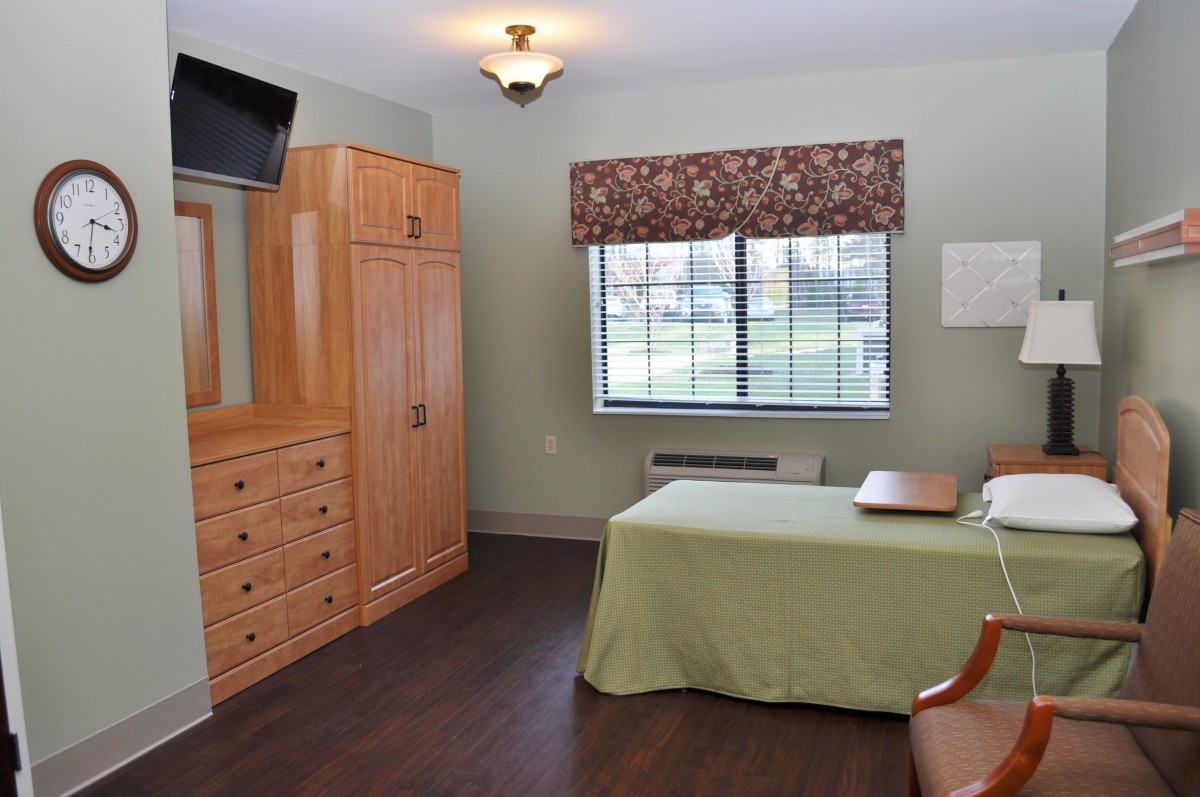 A neatly arranged bedroom with a television, wardrobe, and dresser.