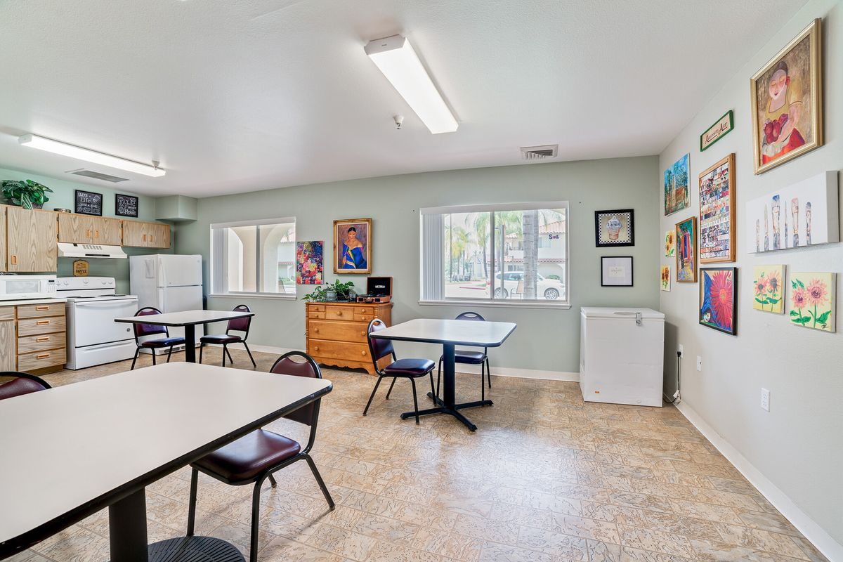 A communal room with tables, chairs, and artwork on the walls.
