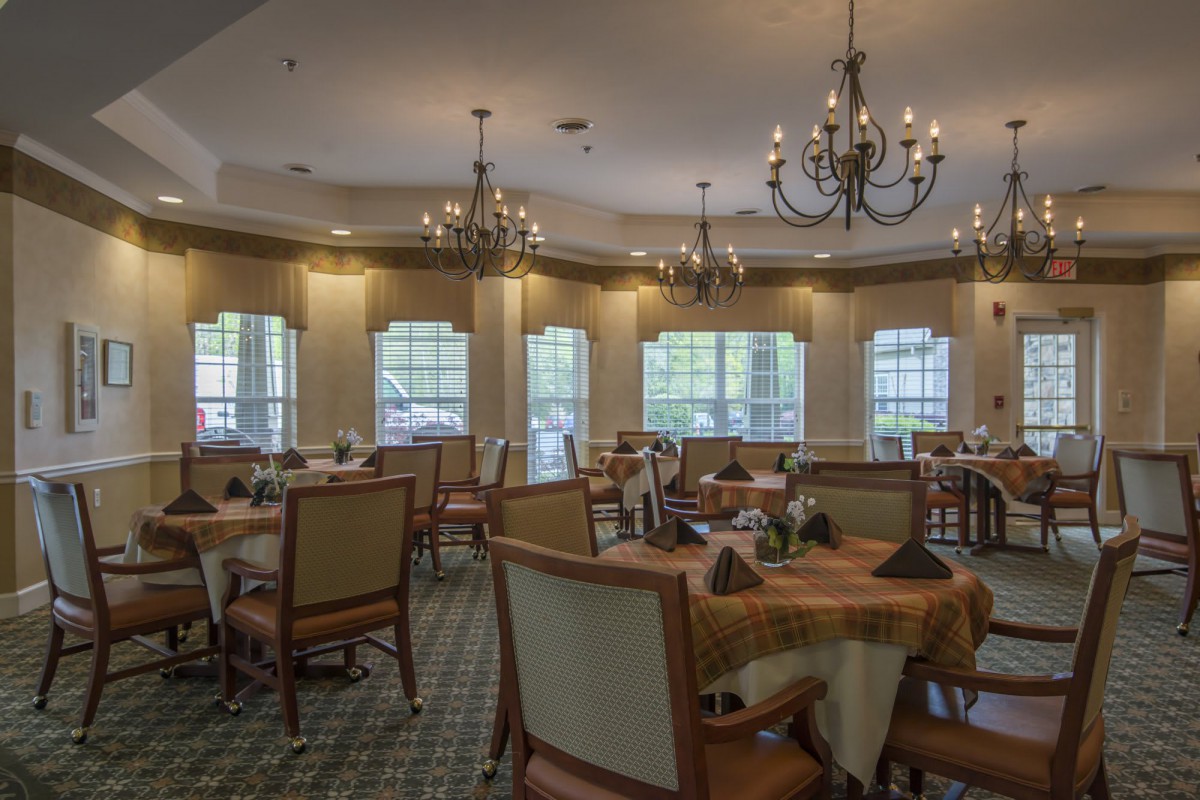 A warmly lit dining room with elegantly arranged tables and chandeliers.