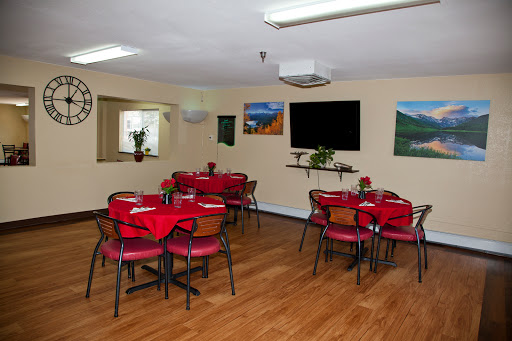A cozy dining area featuring red-covered tables and wooden flooring, perfect for gatherings.