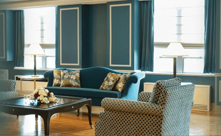 A cozy living room with elegant furnishings, featuring a teal sofa and patterned armchair.