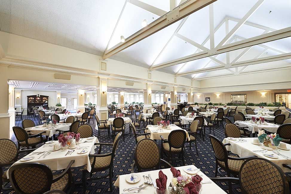 A spacious and well-lit restaurant dining room with neatly arranged tables and chairs.