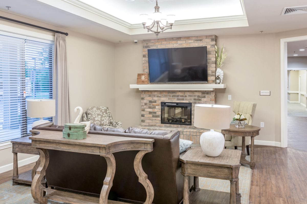 A modern living room featuring a stone fireplace and wall-mounted television, complemented by elegant furniture and decor.