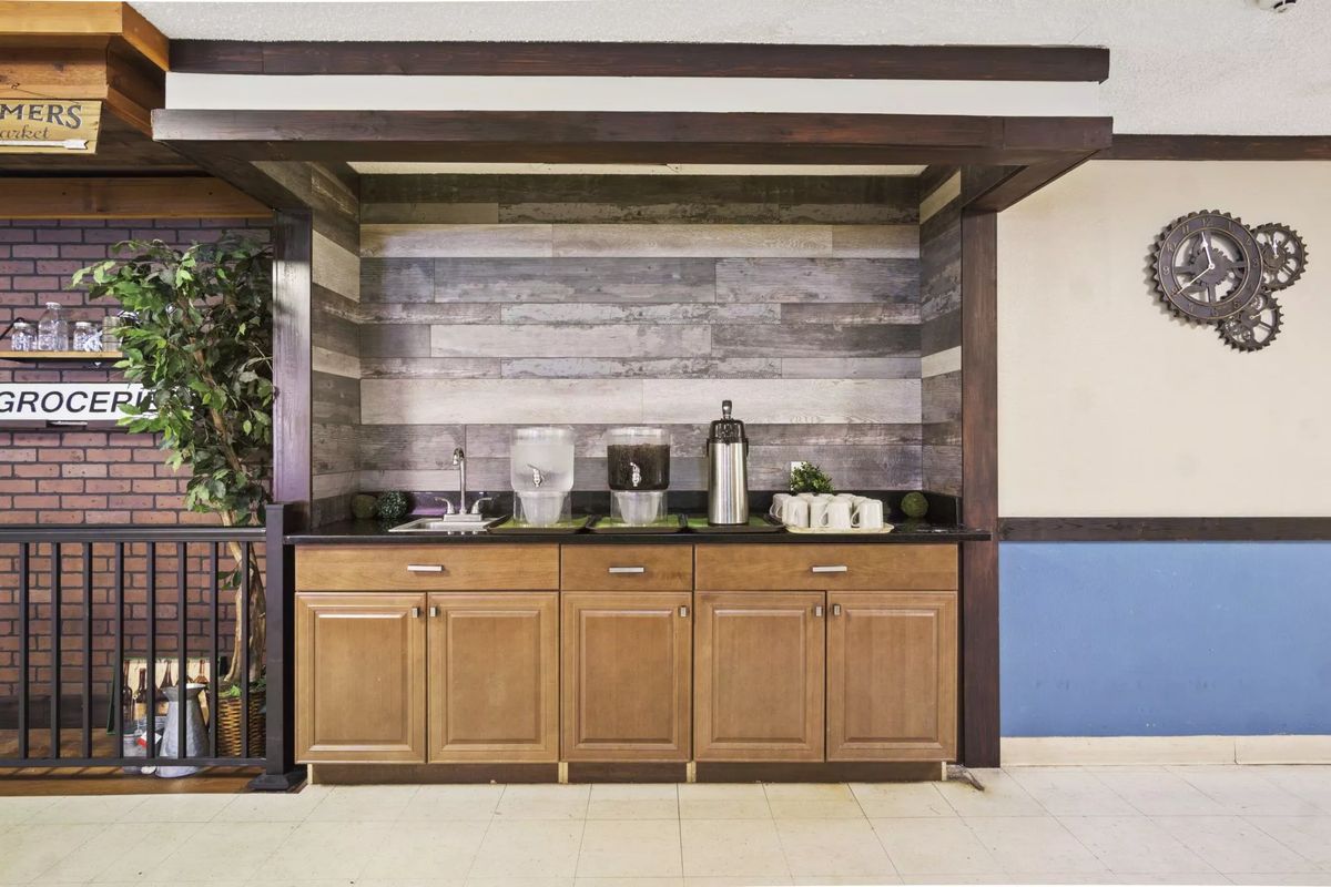A cozy beverage area featuring wooden cabinets and a coffee station with a rustic wood-paneled backdrop.